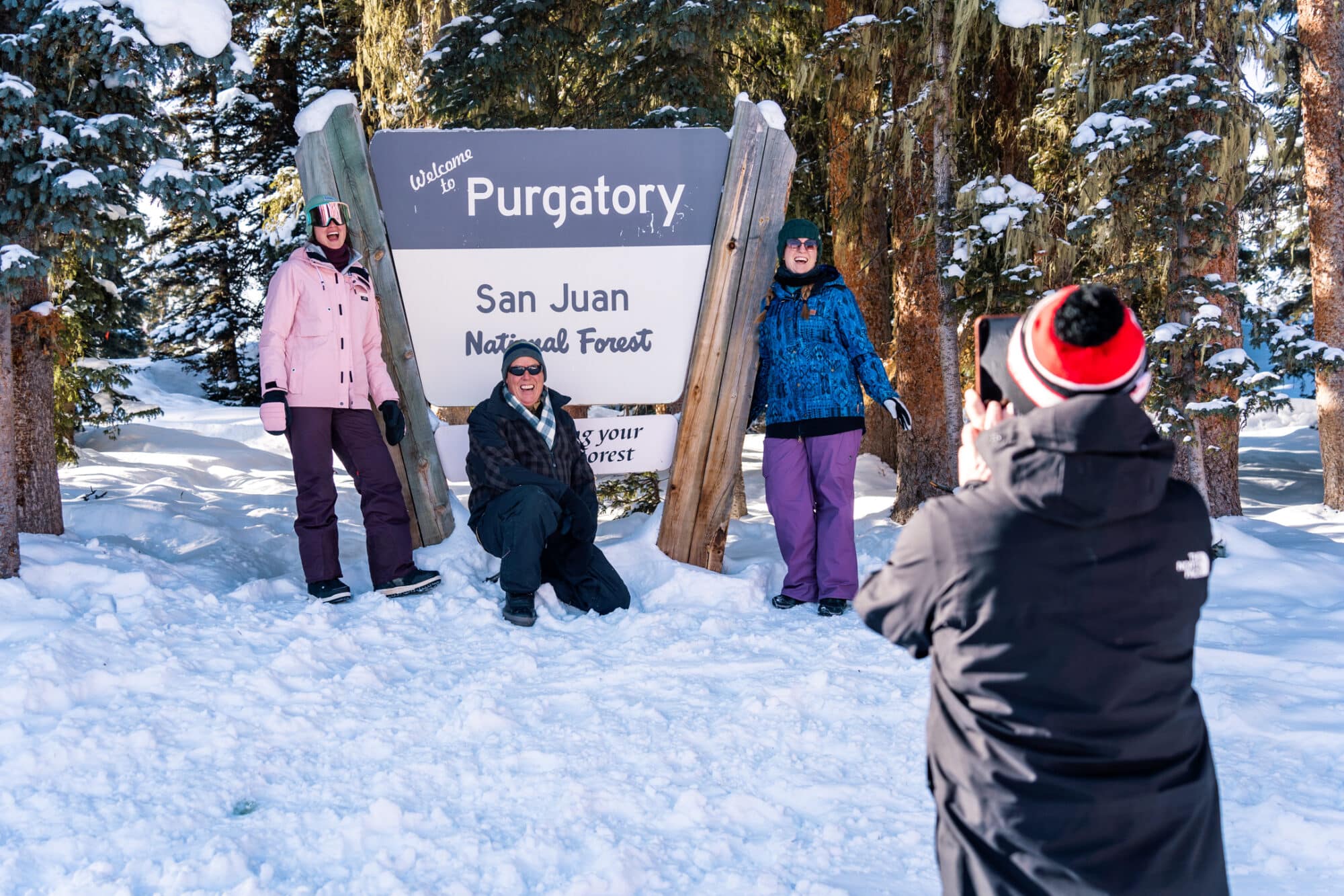 Family poses in front of San Juan National Forest sign at the top of Lift 1