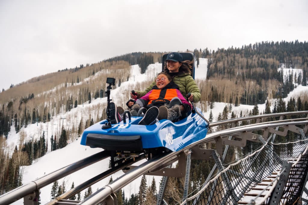 Mom and daughter enjoy the thrilling mountain coaster on a winters day