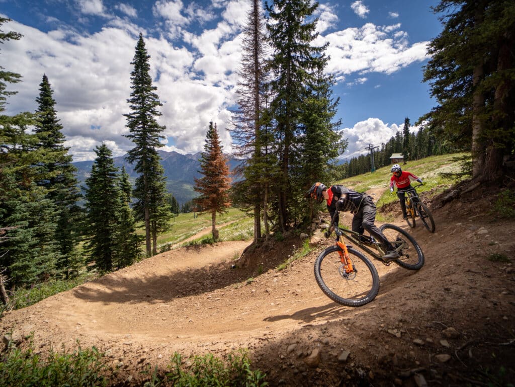 Mountain bike instructor leads the way down a berm in the trail