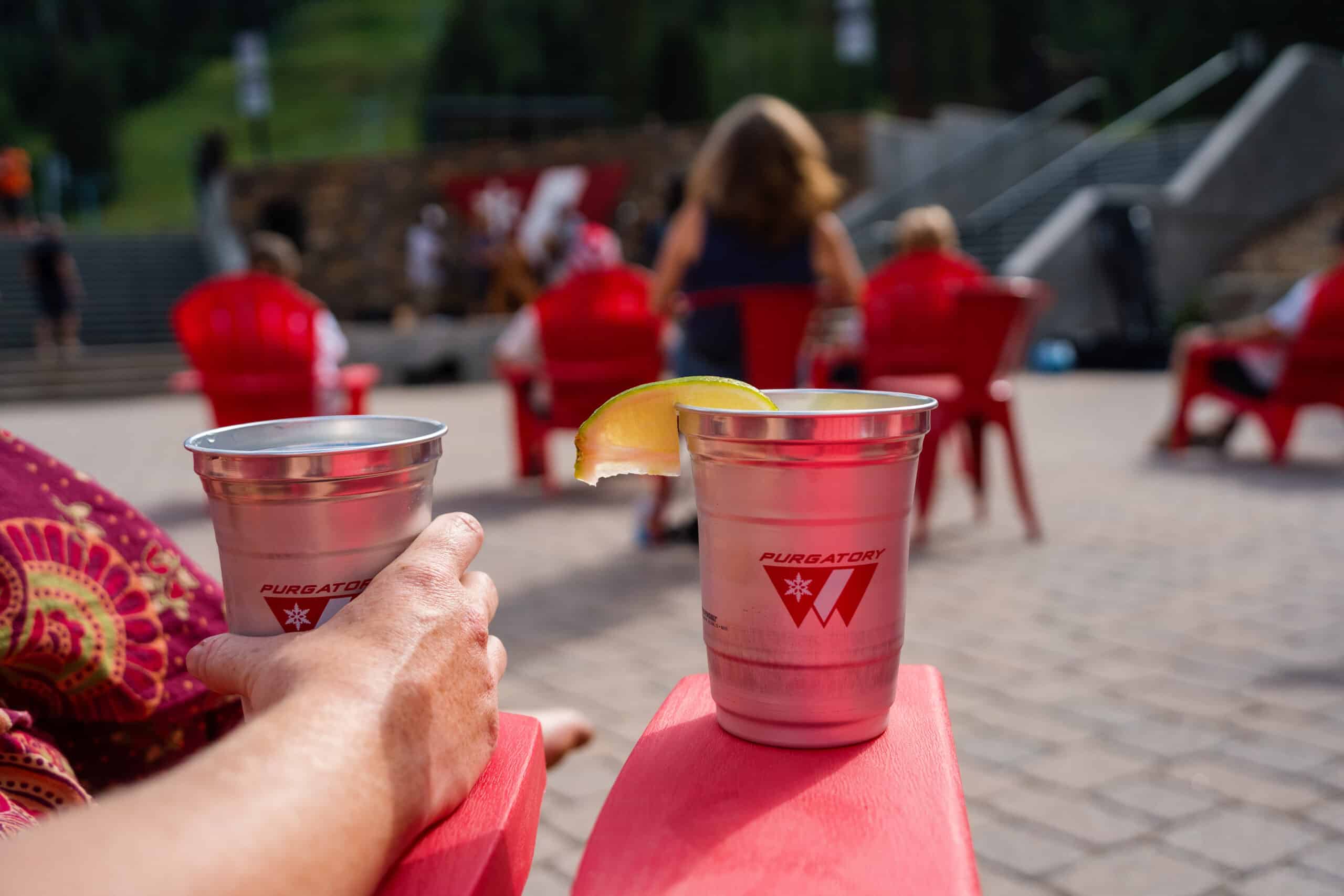 Aluminum beer cups on a red arm rest outside on the purgatory resort plaza