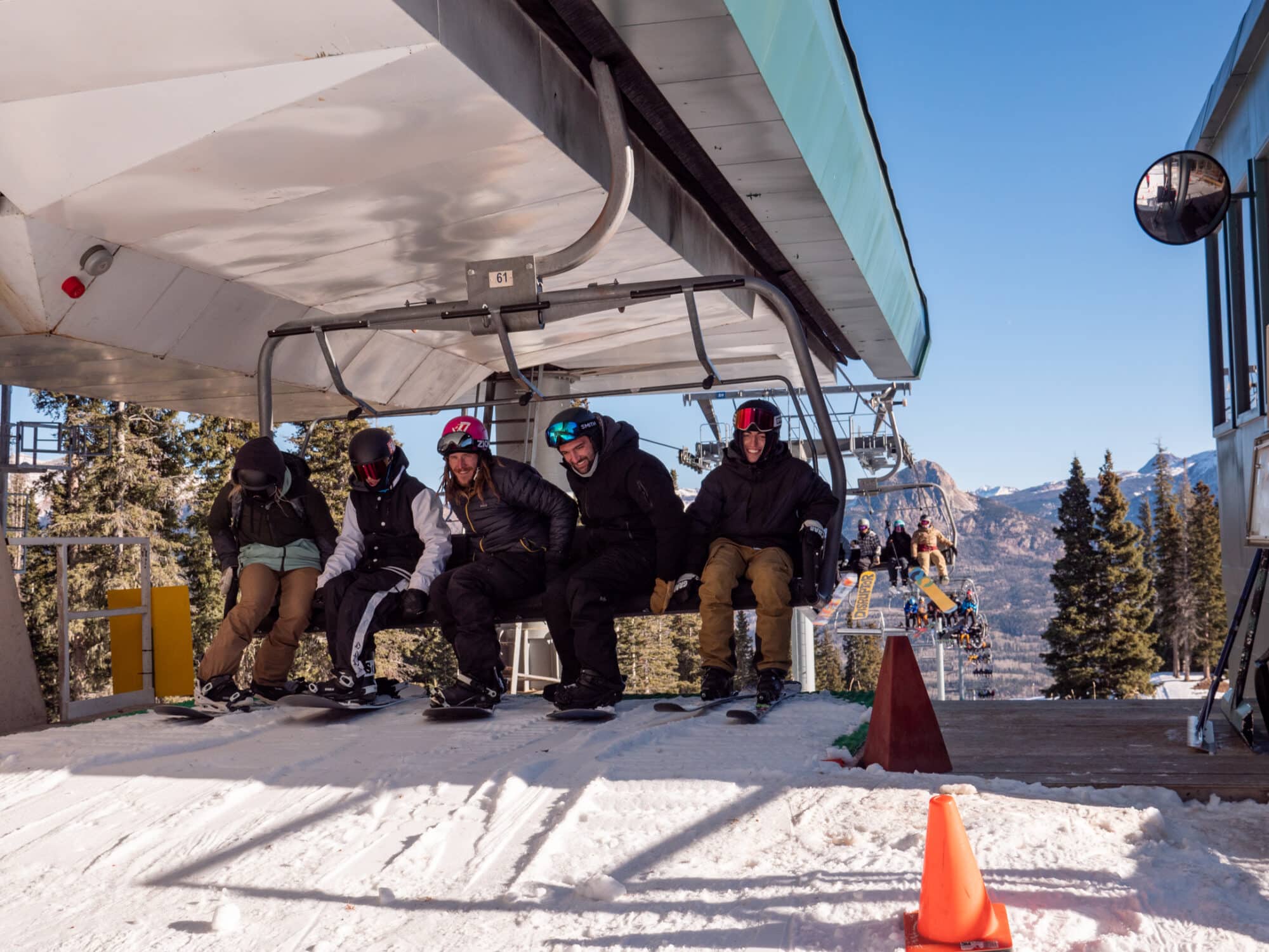 Skiers and Snowboarders smiling and hopping off a lift